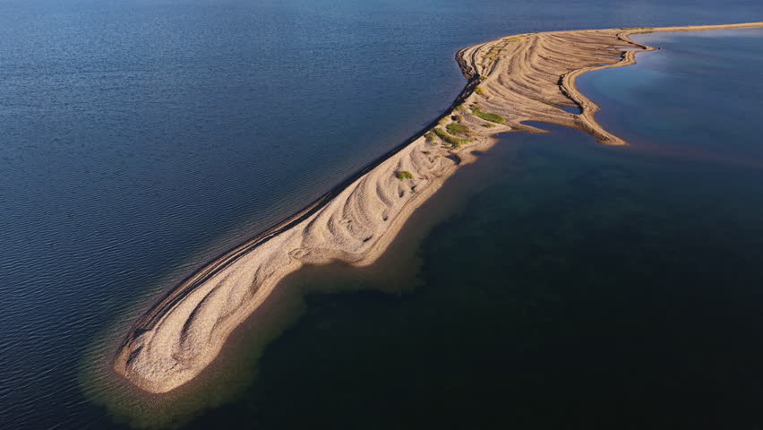 Aerial view drifts above a lone sand spit inside a pristine Abolesheva Bay. Breathtaking calm water rings the arctic shoal of Chukotka as lateral tracking glides past a curling sandbank