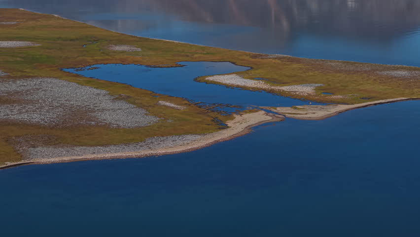 Aerial view glides forward above pristine braided lagoons on an arctic coast. Dolly motion pushes over breathtaking Chukotka wetlands in cool light as Abolesheva Bay unfolds in gravel bars