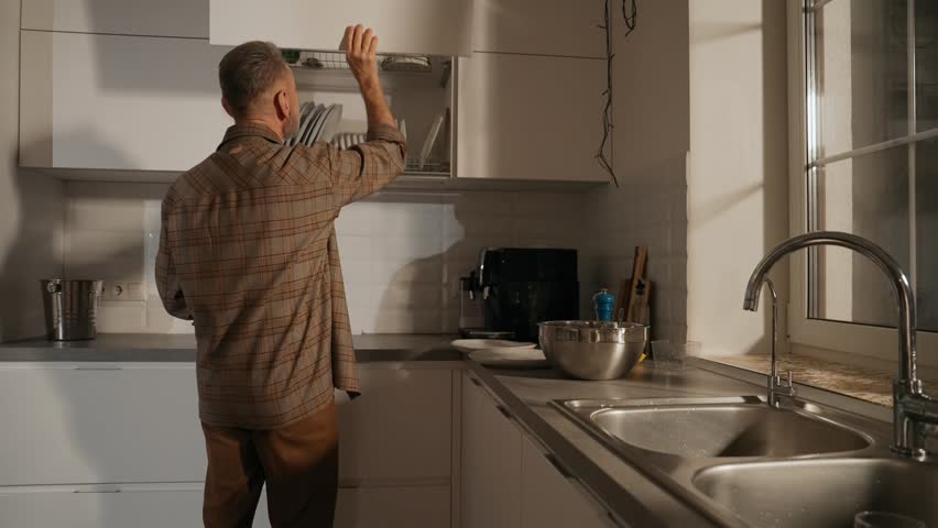 A man closes a drawer and pours food from a bowl onto a plate