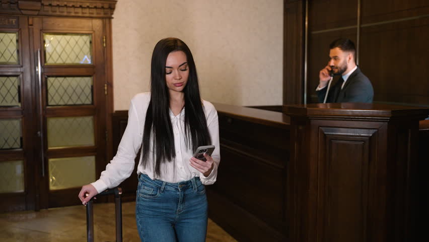 Young businesswoman talking on phone at hotel reception desk