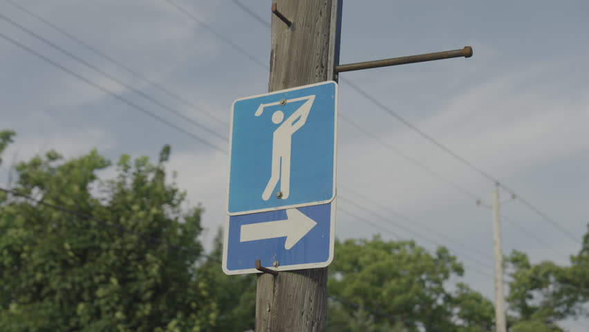 Cinematic shot of a golf course street sign in Truro, Nova Scotia, Canada surrounded by trees and suburban neighbourhood scenery. Peaceful Maritime atmosphere with natural outdoor detail.