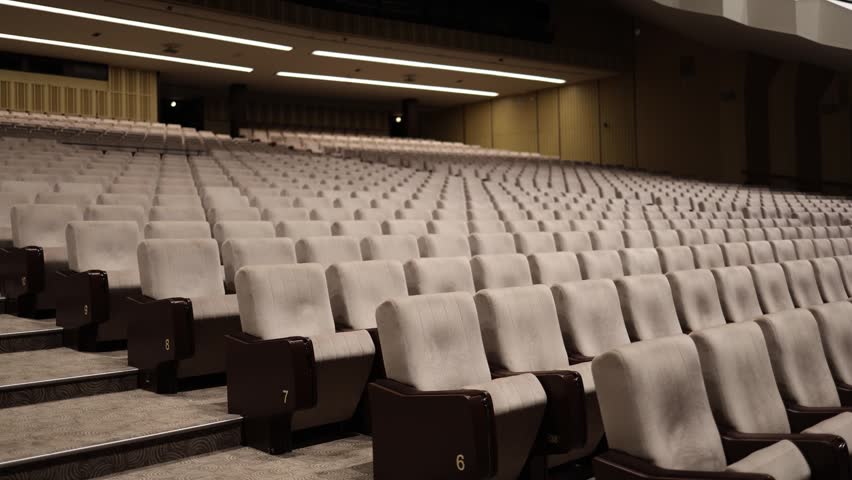 Rows of empty auditorium seats inside modern concert hall with warm lighting and contemporary interior prepared for audience before live performance