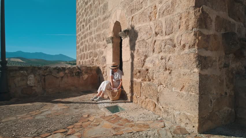 Woman Exploring Historic Spanish Village, Admiring Mountain Views and Planning Her Next Adventure