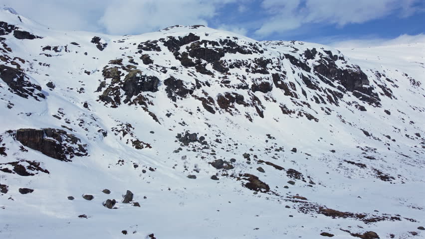 Snow-covered mountain slope with rocky outcrops in the alpine.