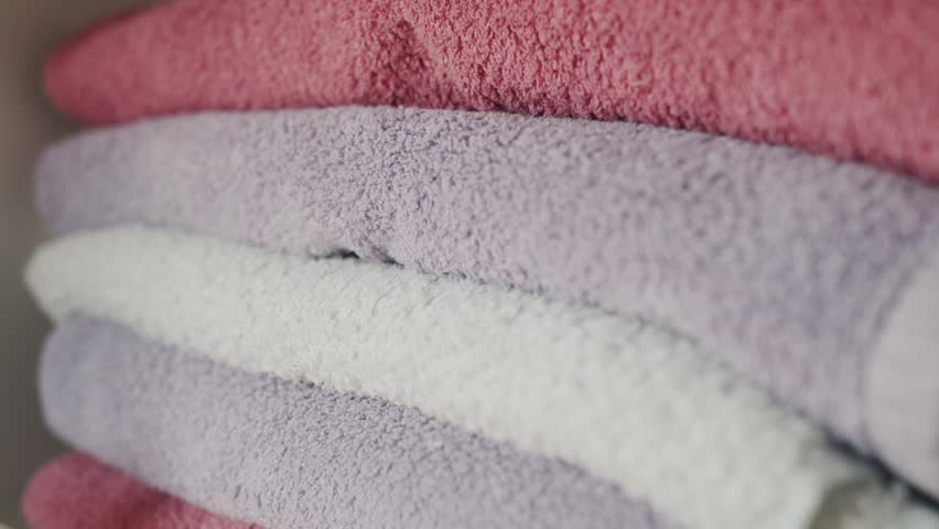 Woman organizing colorful clean towels in closet, soft textile.