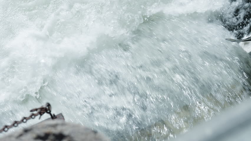A salmon jumps against a rushing waterfall during the annual fall spawning run in the Ganaraska River at Port Hope, Ontario. White foam bubbles surround the fish in the currents.