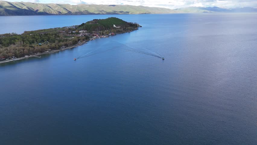 Aerial Drone View of Calm Mountain Lake With Two Floating Boats Under Cloudy Sky 4K.