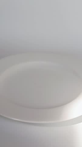Hand picking a chocolate donut from a plate of colorful frosted donuts on a white background