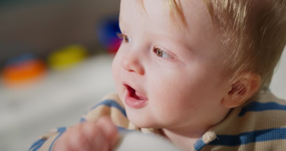 Close-up of a young toddler with light hair interacting curiously with a soft white stuffed toy in a bright indoor setting, showcasing early childhood exploration and sensory engagement