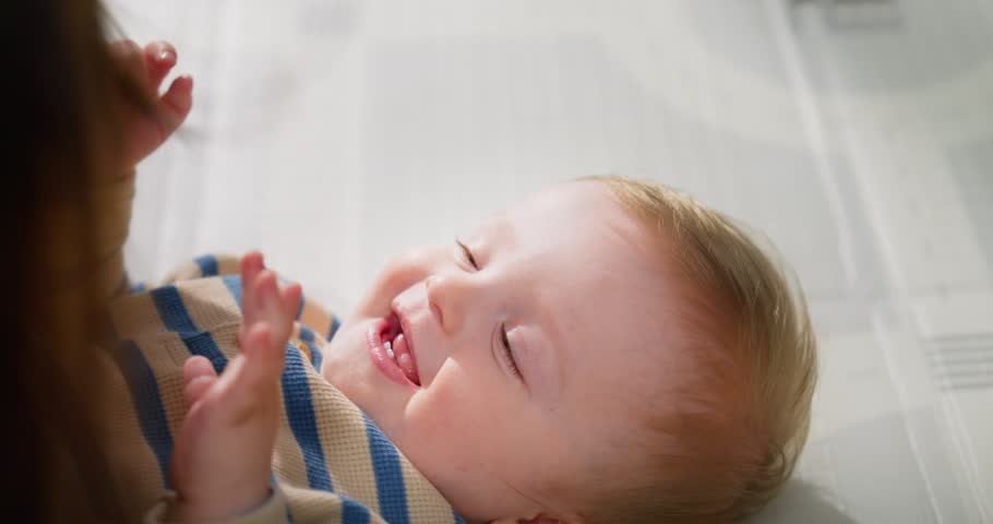 Close-up portraits of a happy baby smiling and laughing while being held and comforted by an adult, capturing moments of joy and bonding in a cozy indoor setting
