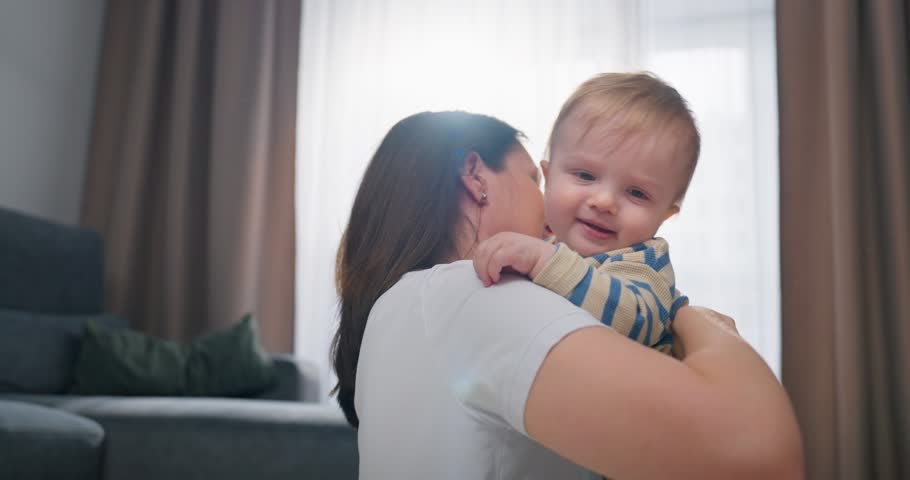 Tender moments of a mother playing and bonding with her smiling baby in a cozy living room, capturing joy, warmth, and affection in a family setting during daytime