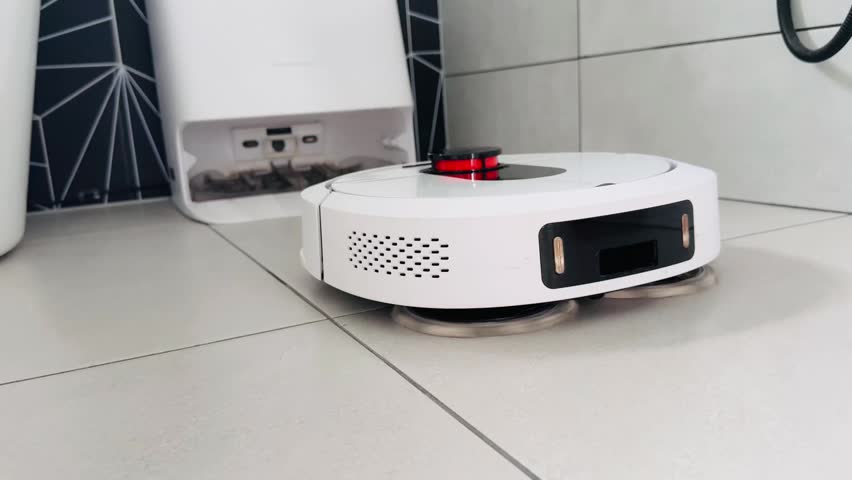 Robot vacuum cleaner navigating tiled floor with charging dock in background