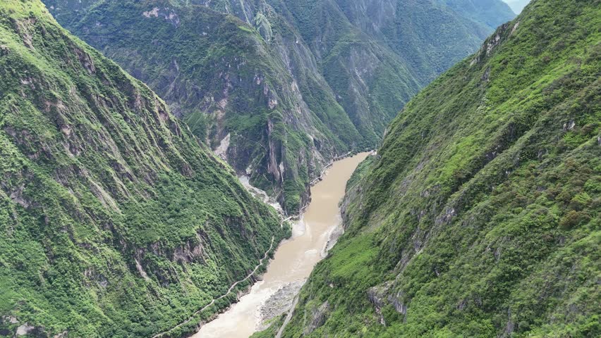 Winding river flowing through Tiger Leaping Gorge mountain canyon, drone tilt up