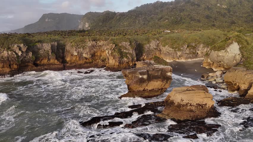 Ocean waves crashing on Pancake Rocks coastline at sunset in New Zealand, Drone flying backwards, Drone flying backwards orbital