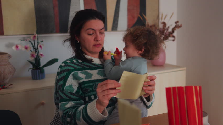 Parent laughing as young child reaches toward her cheek, warm domestic interaction expressing love, spontaneity and everyday family life