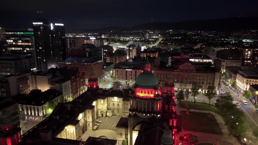 Side-on reversing aerial GV of Belfast City Hall in Belfast City Centre at night. Produced in 3840x2160 4K and with Rec709 color.