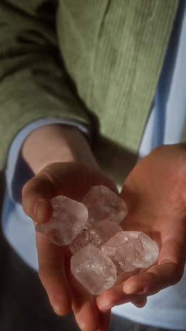Vertical shot of unrecognizable person holding ice in hands and rolling them around playfully enjoying cooling sensation, story format