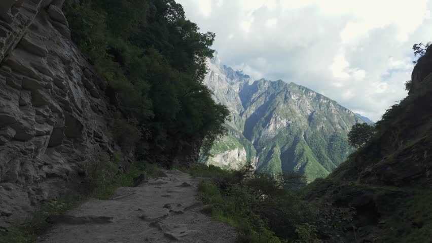 Hiking pov along Tiger Leaping Gorge high trail through rugged mountain pass