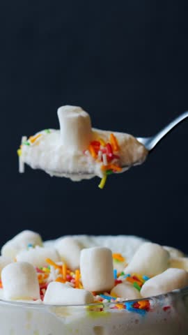 Detailed capture of spoon with toppings. Upclose image showcasing marshmallow and rainbow sprinkles. Professional composition highlighting spoon with creamy froth and colorful garnish