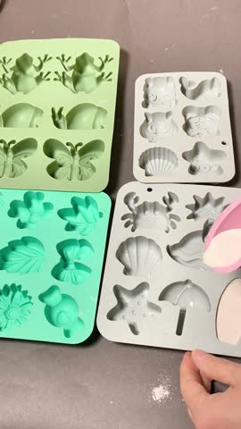 Pouring plaster mixture into silicone molds, various shapes including butterflies, shells, and flowers, hands filling molds with liquid plaster, DIY crafting process,creative in home workshop.vertical