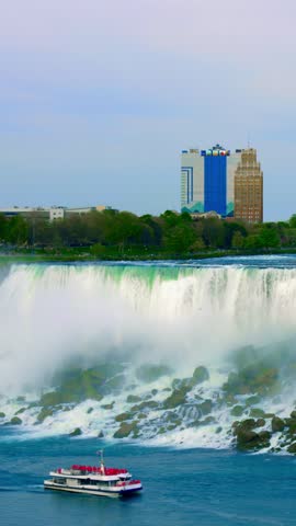City and waterfall. Skyscrapers and rushing water create picturesque urban landscape scene. Boat approaches cascading waterfall amid city backdrop featuring towering buildings and flowing water