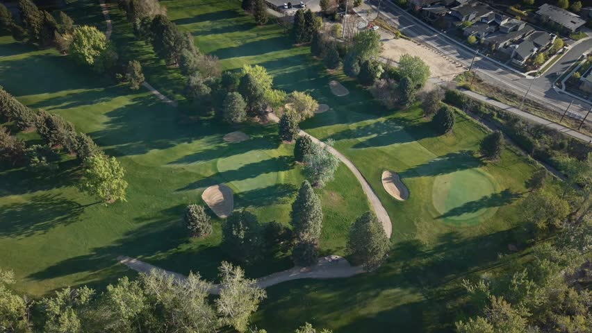 High altitude spring morning drone shot of beautiful fairway at Warm Springs Golf Course in Boise, Idaho. Lush green grass stretches across the course under soft morning light with scenic spring surroundings. Peaceful aerial view ideal for golf lifestyle, sports, travel, and Idaho scenery content.