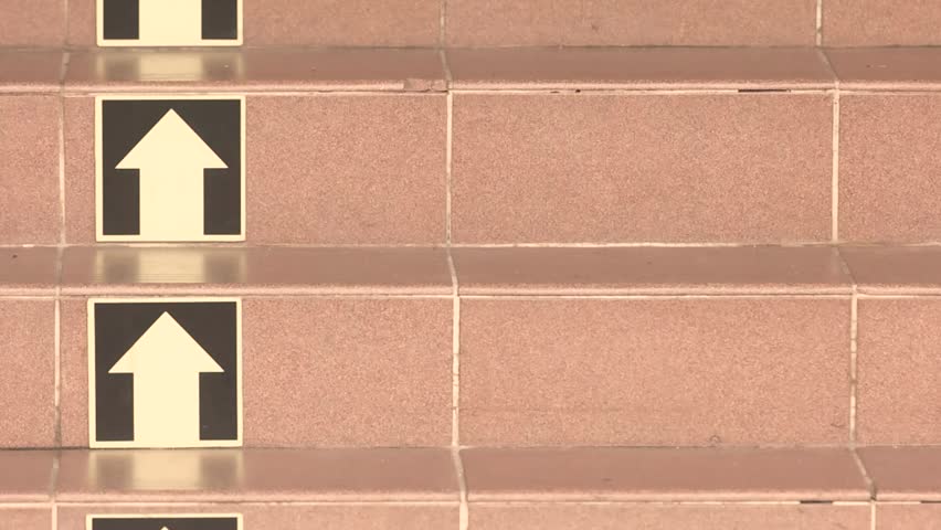 Tiled staircase with arrow signs guiding direction for upward steps navigation