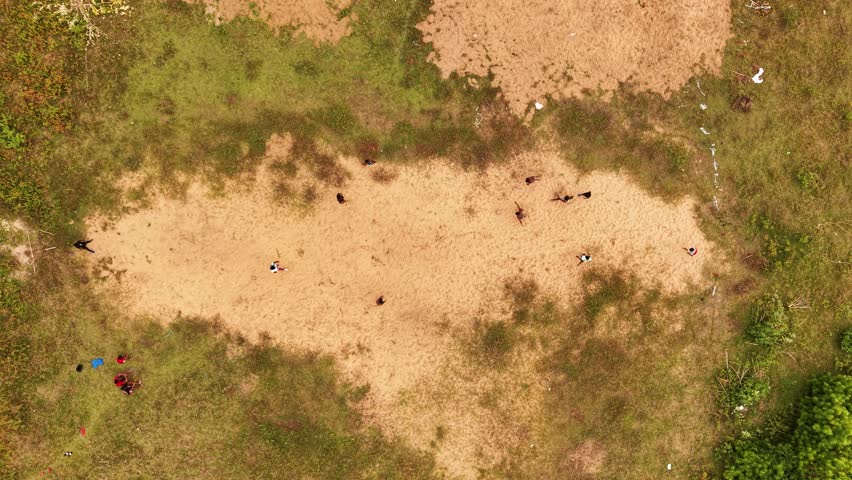 Aerial view of people playing cricket on a sandy patch surrounded by green grass and vegetation in Galle, Southern Province, Sri Lanka.