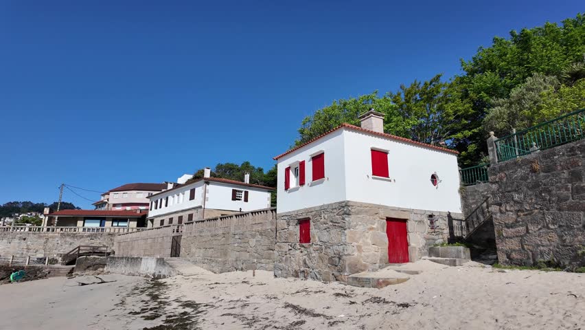 Coastal town buildings lining a sandy beach and bay filled with fishing boats