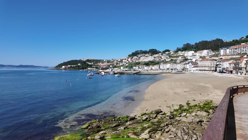 Coastal town buildings lining a sandy beach and bay filled with fishing boats