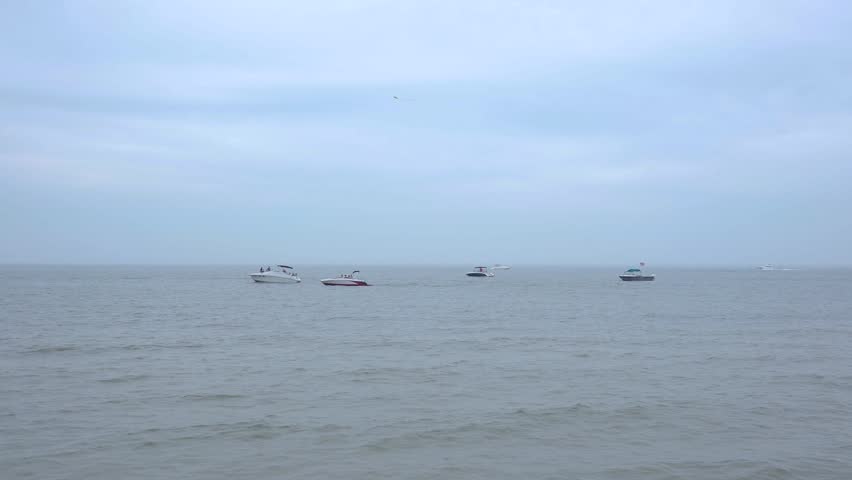 Lake Michigan overcast water view from Grand Haven beach during Kite Festival with boats visible on horizon. Misty grey lake waters with watercraft in distance at Michigan lakeshore during annual kite festival event.