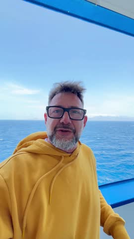 A happy man smiles on a boat trip across the clear blue ocean under a bright sky, enjoying his summer vacation and the refreshing sea breeze.