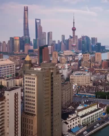 A panoramic view of the Shanghai cityscape at dusk, showcasing its iconic modern skyscrapers and older buildings.