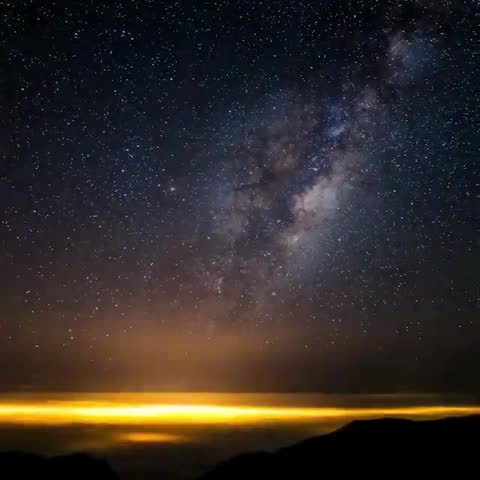 A stunning view of the Milky Way galaxy stretching across the night sky above a glowing horizon.
