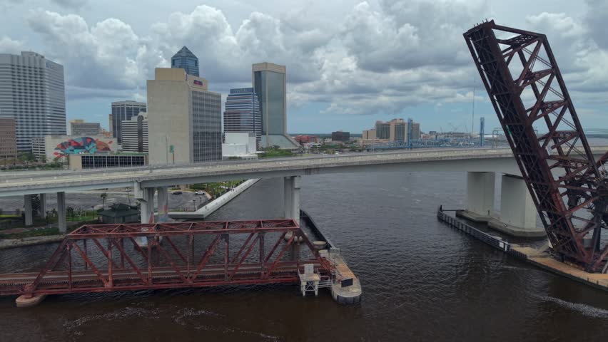 Aerial view of the Jacksonville skyline featuring the Acosta Bridge and the raised railroad bridge over the St. Johns River under a cloudy sky Jacksonville, Florida, United States.