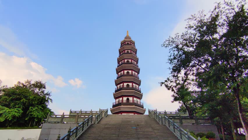 Low angle steady shot of traditional Chinese pagoda tower in lush green park