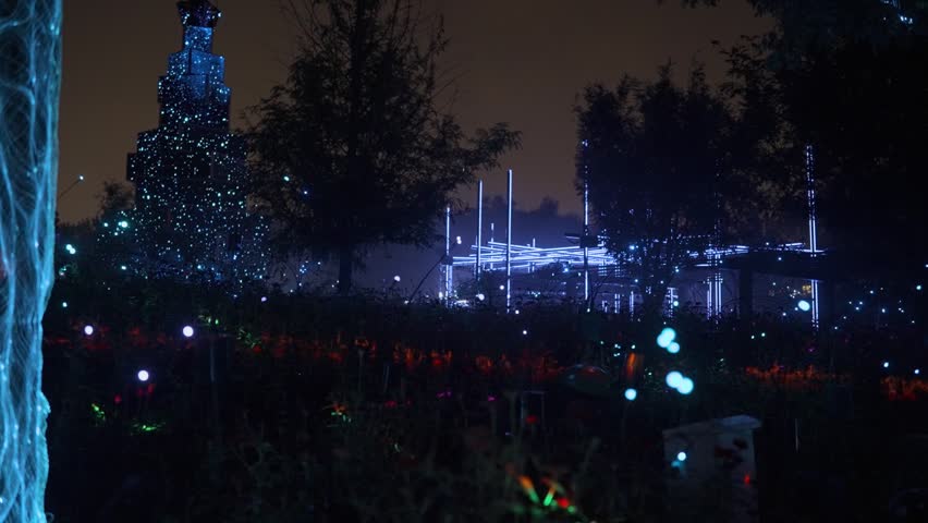 Fireflies glowing in a dark park at night with illuminated garden light structures