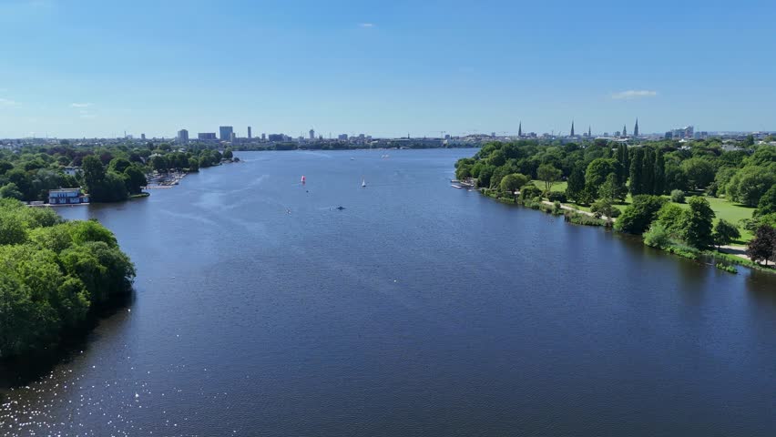 Aerial view of the Aussenalster lake surrounded by lush green parks and the city skyline under a clear blue sky in Hamburg, Hamburg, Germany.