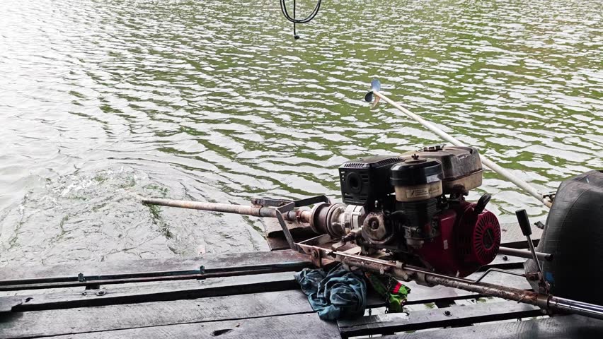 Long tail boat gasoline engine on wooden floating deck.