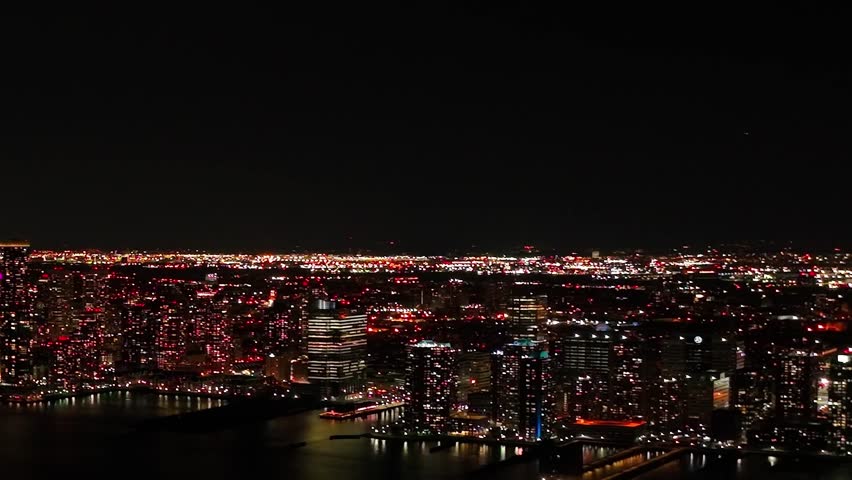 Long distance view of the illuminated waterfront of Jersey City across the Hudson River from Manhattan.