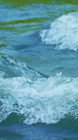 Powerful river rapids creating energetic waves and foaming blue water patterns.