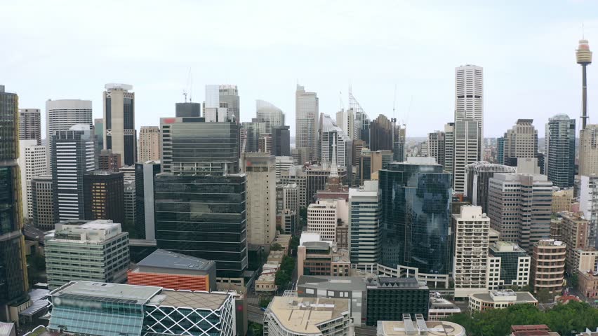 Dynamic zoom out movement showcasing dense urban architecture in New South Wales Australia. Cinematic aerial view of skyscrapers financial district harbor wharves and iconic city landmarks.