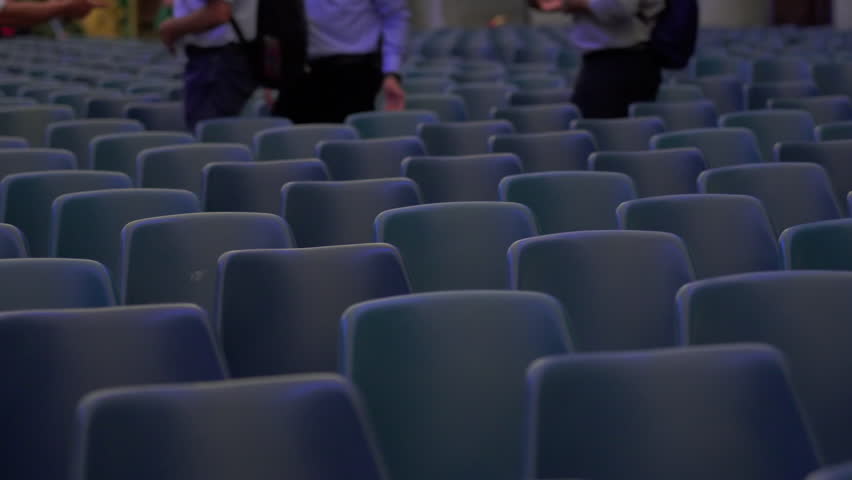 Wide view of numerous empty blue chairs arranged in symmetrical rows inside spacious hall ready for audience or large scale event