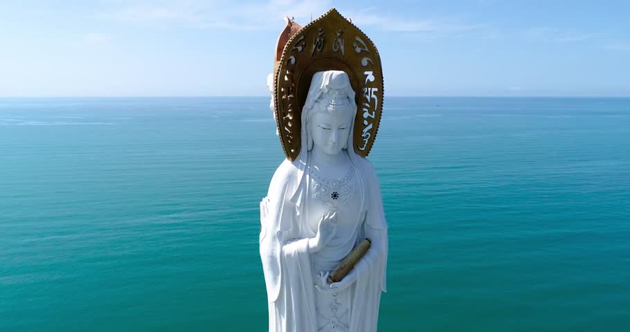 Aerial drone footage of the famous Nanhai Guanyin statue located in the Nanshan Cultural Tourism Zone in Sanya, Hainan Province, China. The towering Buddhist landmark overlooks the South China Sea and attracts visitors, pilgrims, and tourists from around the world.