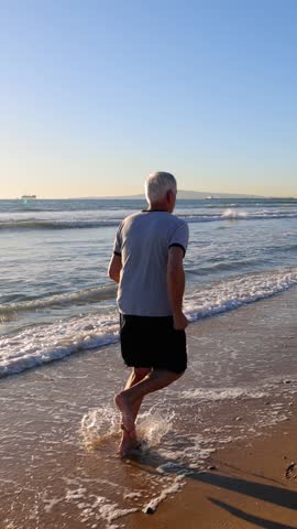 64 year old man getting his exercise at the beach at sunset. Slow Motion. Vertical Video.