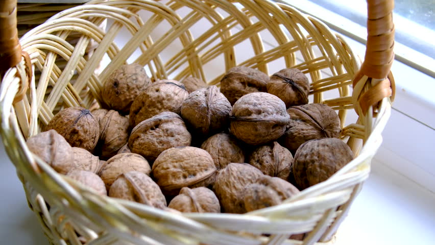 Wicker basket filled with walnuts on sunny windowsill creating cozy rustic home atmosphere