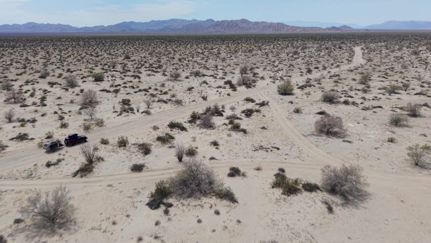 An SUV tows a teardrop camper trailer through the open desert landscape near El Salar salt flats in Baja California.