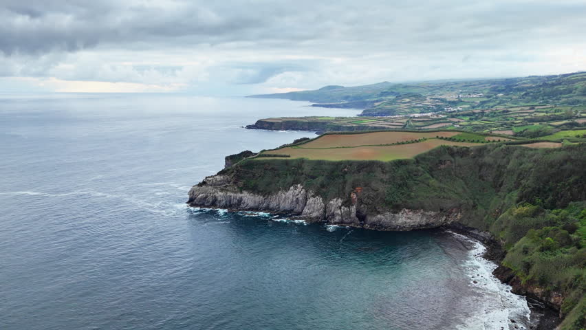 Aerial view of coastal cliffs and agricultural fields above ocean shoreline, Azores, Atlantic island landscape
