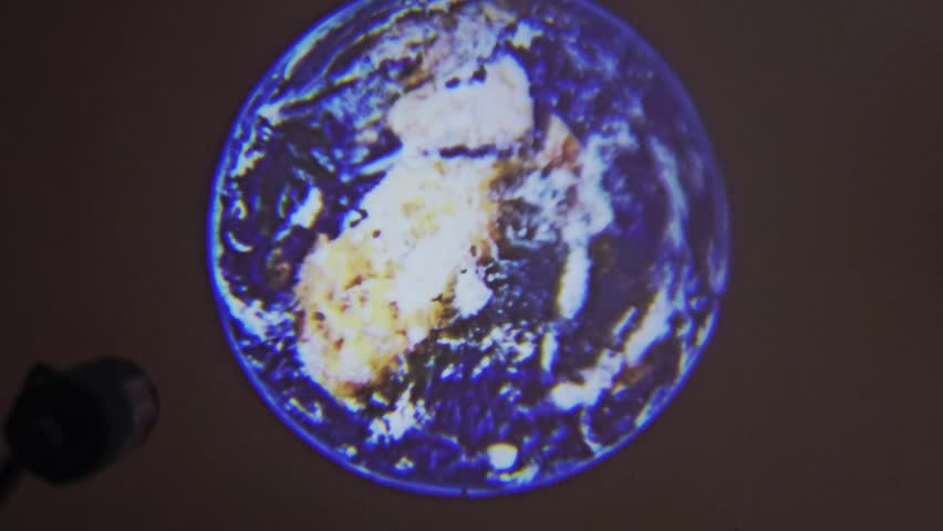 a projection lamp illuminating an image of planet Earth on a flat surface, mimicking the iconic of Blue Marble view from space