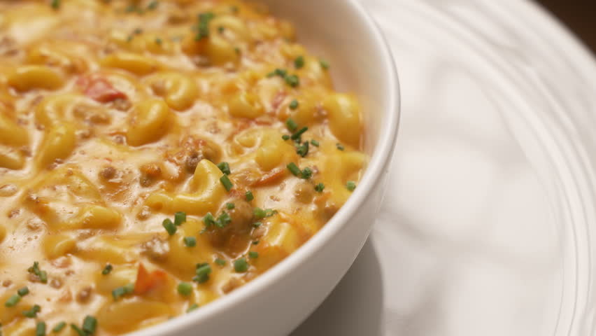 Creamy homemade macaroni and cheese with ground beef and chives served in a white ceramic bowl, fa01